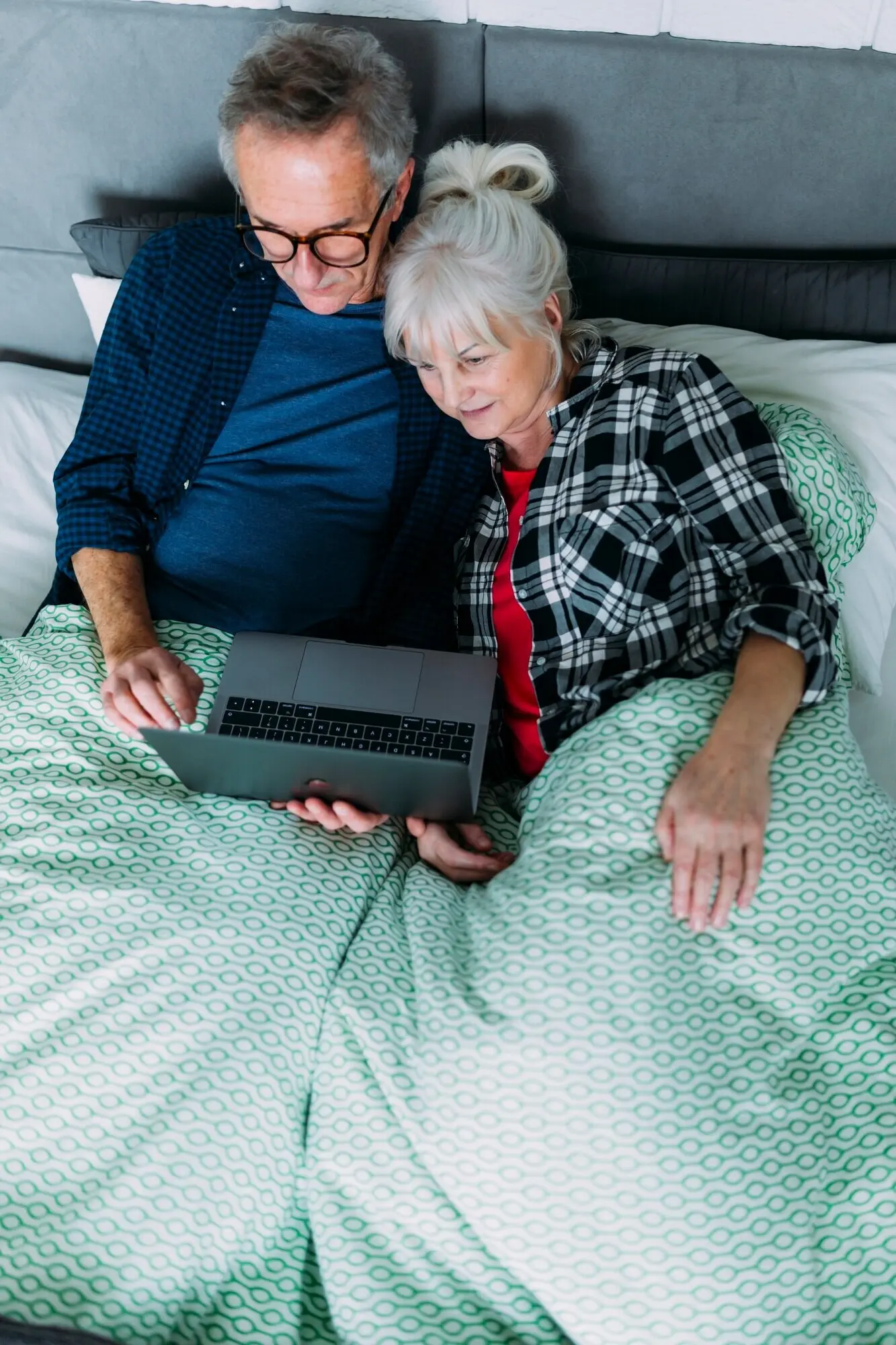 Draufsicht auf ein älteres Paar im Bett mit einem Laptop